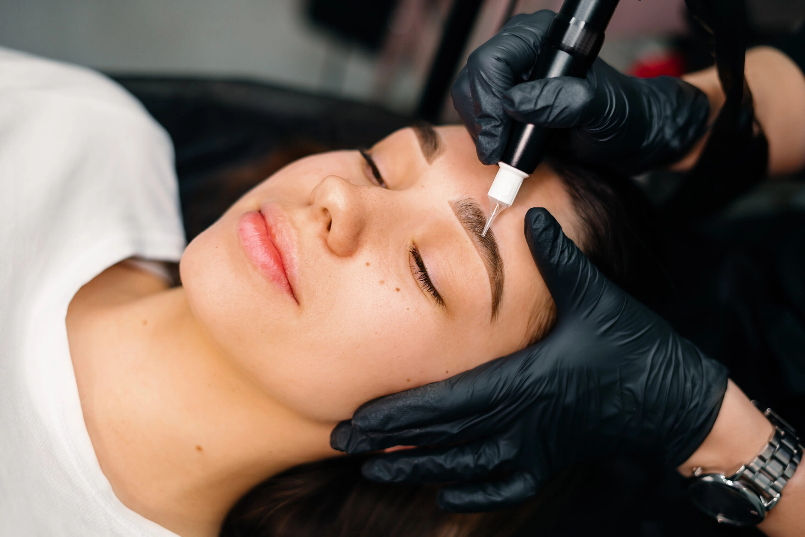 Woman receiving eyebrow microblading treatment
