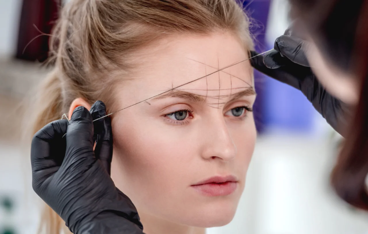 A woman getting her eyebrows shaped by threading.